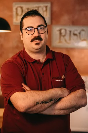 Mitarbeiter mit Brille und rotem Poloshirt der Osteria Antico Il Mattone