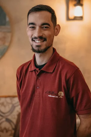 Lächelnder Mitarbeiter mit Bart im roten Poloshirt der Osteria Antico Il Mattone