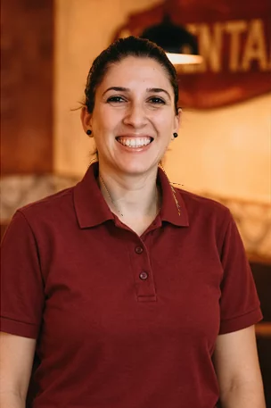 Lächelnde Mitarbeiterin im roten Poloshirt der Osteria Antico Il Mattone