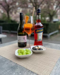 Wein und Aperol Spritz mit Oliven auf einem Terrassentisch